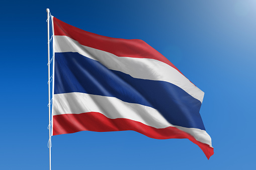 The National flag of Thailand blowing in the wind in front of a clear blue sky