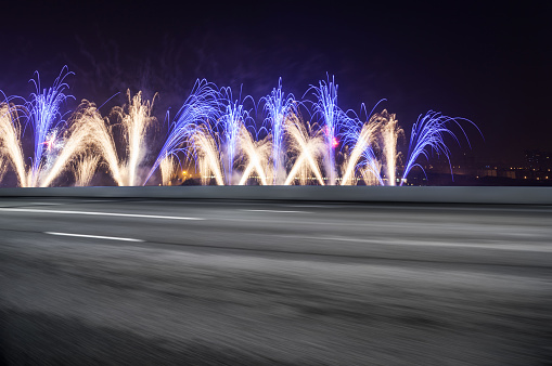 night scene of modern city with fireworks from empty road