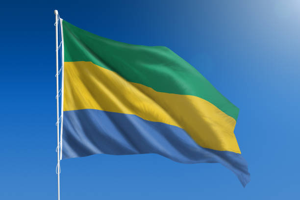 The National flag of Gabon blowing in the wind in front of a clear blue sky