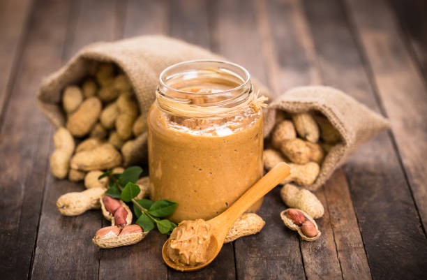 Peanut butter and peanuts on the wooden table stock photo