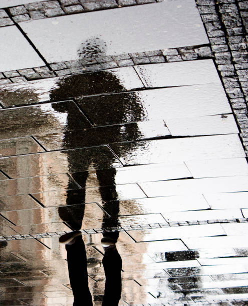 istock Reflection of a man in rainy sidewalk pavement 670951138