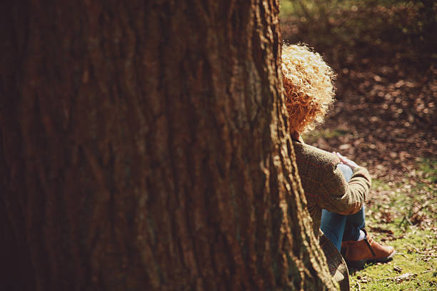 istock Rear View Of Woman Sitting By Tree Trunk 670951793