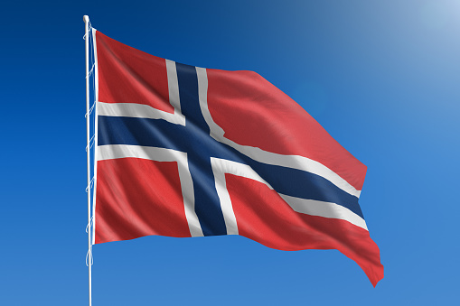 The National flag of Norway blowing in the wind in front of a clear blue sky