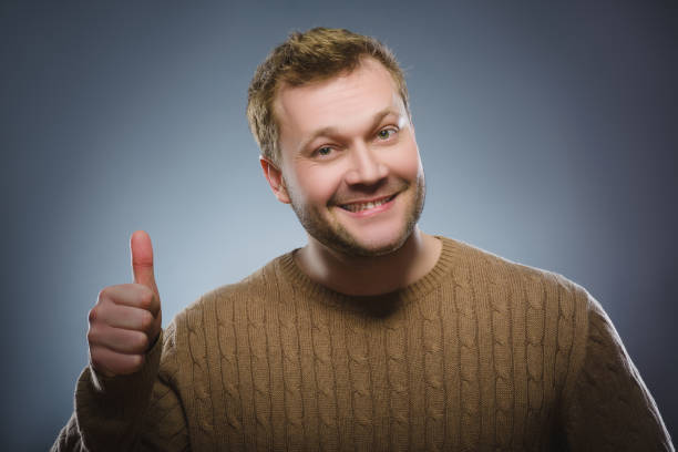 Closeup portrait successful happy boy show thumb up isolated grey background. stock photo