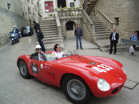 San Marino, Italy - May 07, 2010: Sports cars are driving down narrow streets. People are looking at the cars.