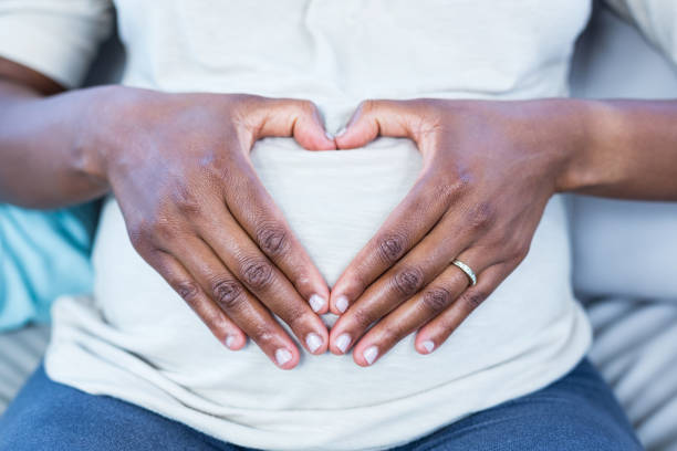 istock Mid section of woman making heart shape on her belly 670961038