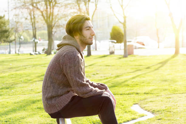 istock Young man daydreaming on the bench in the park 670971372