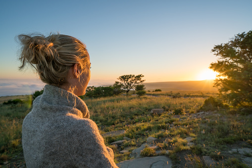 One young woman looking at sun rising in the savannah, Mountain Zebra national park in South Africa.