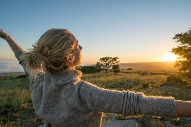 istock Young woman arms outstretched at sunrise 670973548