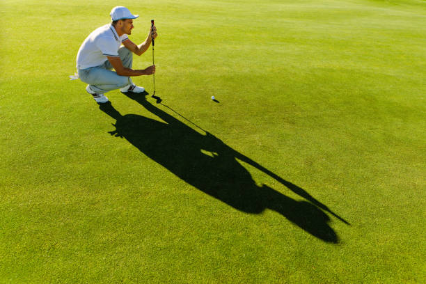 istock Male golfer check line for putting golf ball 670973564