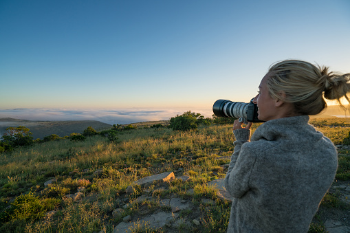 One young woman taking a picture of the spectacular mountain scenery in Mountain Zebra national park in South Africa.