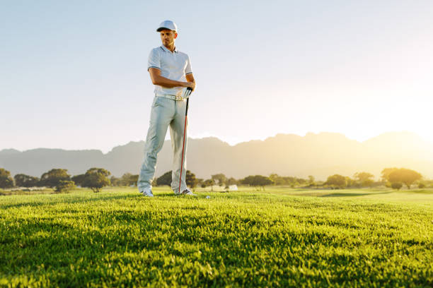 istock Male golfer with golf club on field looking away 670973876