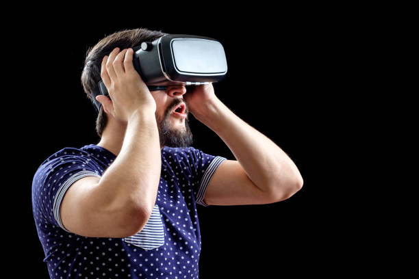 istock Man in blue dotted T-shirt wearing virtual reality 3d-headset isolated on black 670975364