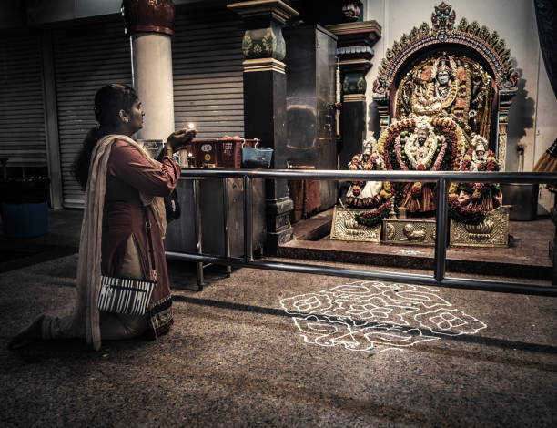 Woman praying  inside Sri Mariamman Temple in Chinatown Singapore. This is the oldest hindu temple of the city. It was founded in 1827