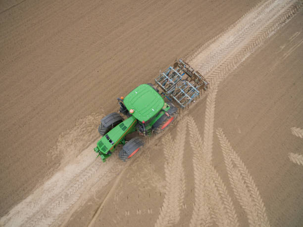 istock tractor - aerial view of a tractor at work cultivating a field in spring 670982484