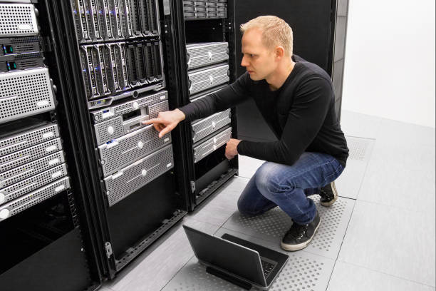 It consultant work with laptop in datacenter It engineer or consultant working with laptop and maintaining servers in data center. computer shop stock pictures, royalty-free photos & images