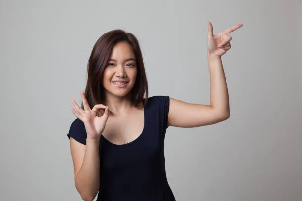 istock Young Asian woman point and show OK. 670990828