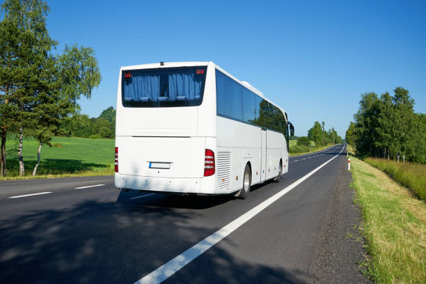 istock White bus moving on asphalt road lined avenue of trees 670996012