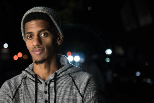 A candid portrait of a young, black man beneath Brooklyn Streetlights