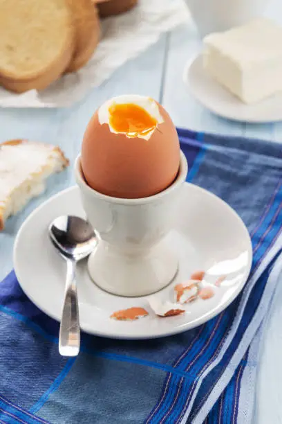 A vertical photo of soft-boilled egg in an egg-cup