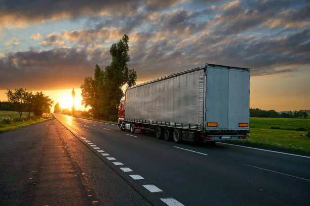 istock Truck driving toward the setting sun on the road 671010018