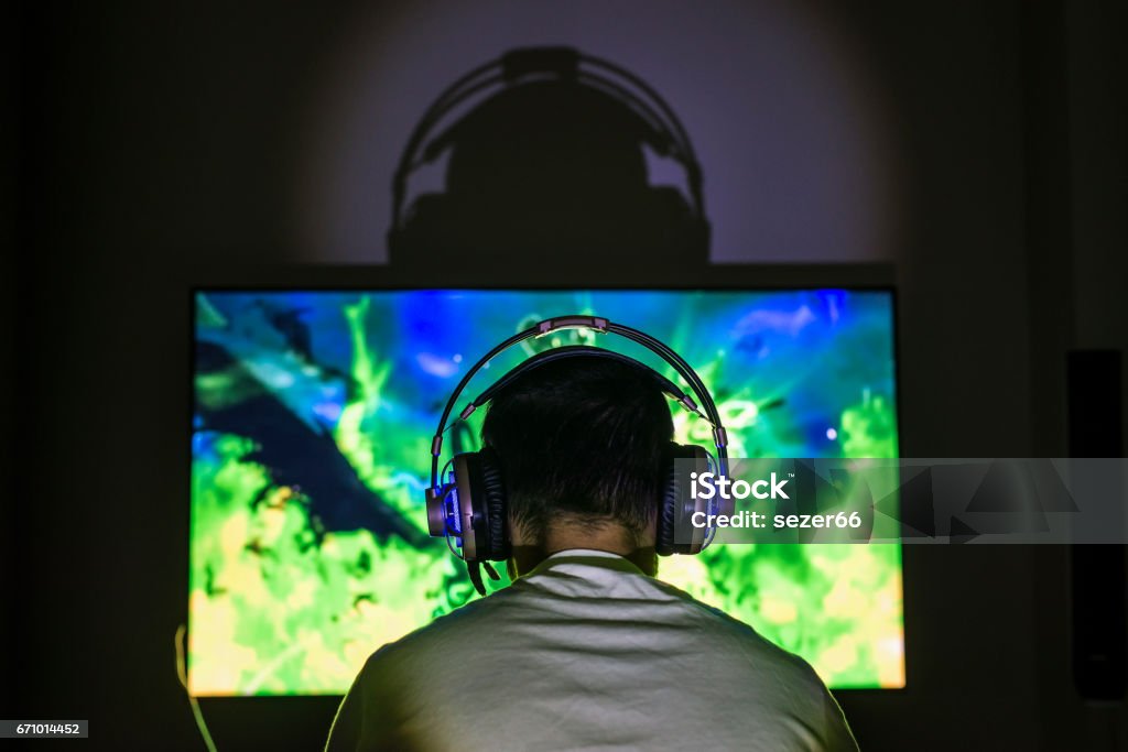 Young gamer playing video game wearing headphone. Young gamer playing video game wearing headphone.Young gamer playing video game wearing headphone. Gamer Stock Photo