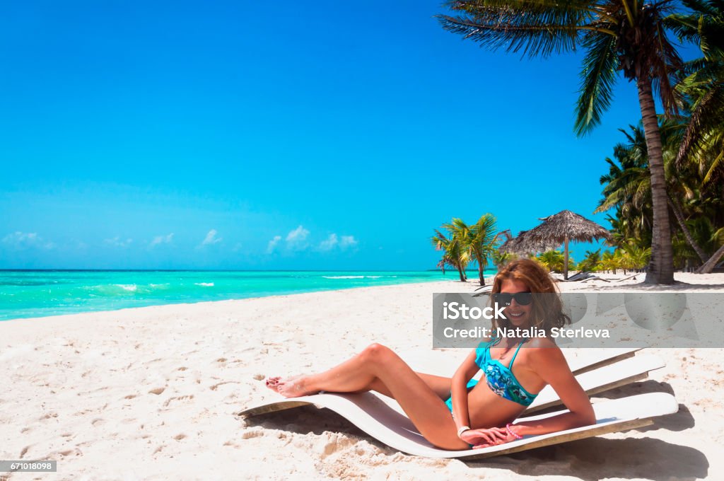 Entspannen Sie sich auf einem Liegestuhl am Strand schöne Frau - Lizenzfrei Baum Stock-Foto