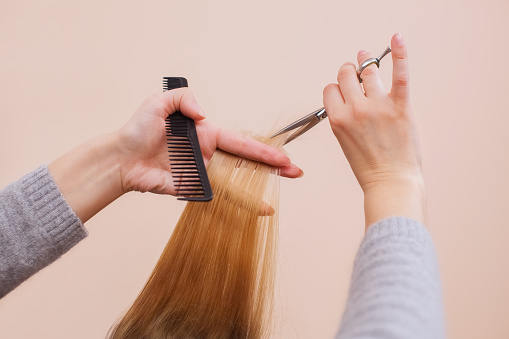 peluquero hace un corte de pelo con tijeras de pelo a una niña photo