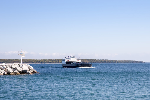 Car ferry on Lake Michigan passing by a stone breakwater in Door County, Wisconsin.  Copy space in sky if needed.  Washington Island is seen in the background.