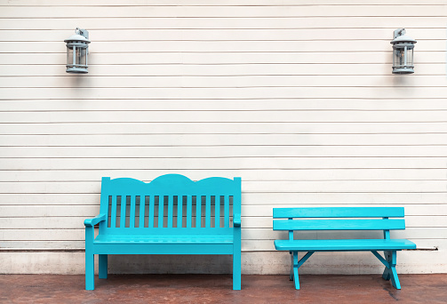 two Light blue wooden bench. White wall.