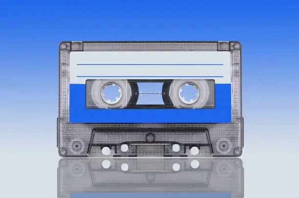 analog audio cassette stands on blue-grey background with reflection