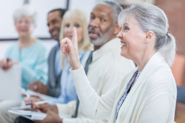 istock Cheerful senior woman asks question during seminar 671032496