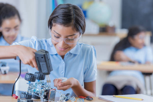 istock Cheerful private STEM schoolgirl works on robot 671034874