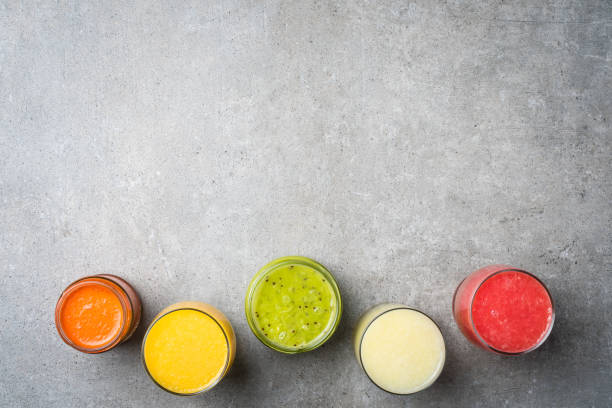 istock Glasses of fresh juice on gray stone table. 671042422