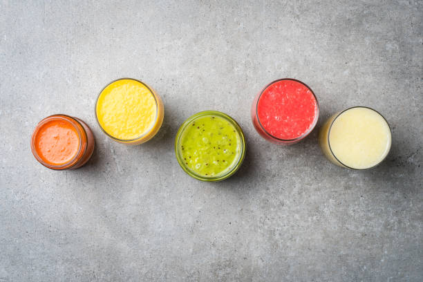 istock Glasses of fresh juice on gray stone table. 671044650