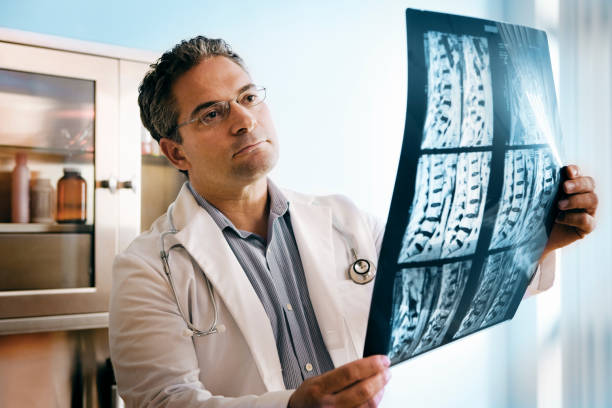 Doctor Doctor looking at MRI of spinal cord. spinous process stock pictures, royalty-free photos & images