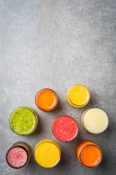 istock Glasses of fresh juice on gray stone table. 671054880