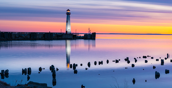 Boat cruises past scenic Wawatam Lighthouse in colorful predawn light, Saint Ignace, Upper Michigan.