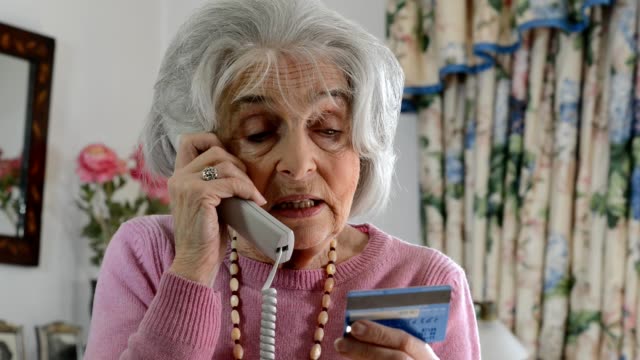 Confused senior woman giving out credit card details over the phone