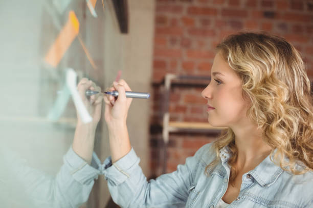 istock Creative beautiful businesswoman writing on board in office 671074454