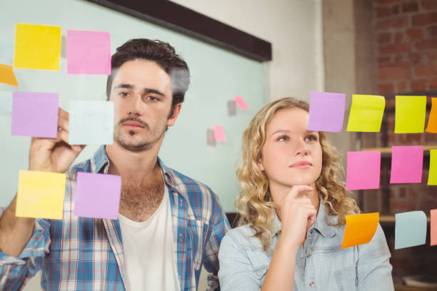 istock Businessman writing on paper while women reading in office 671077422