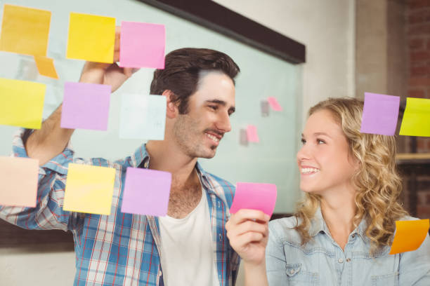 istock Smiling business people touching sticky notes on glass in office 671077488