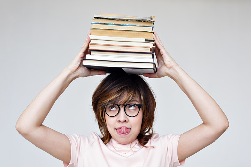 asian girl with a pile of books on her head.