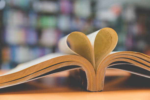 istock old book page in heart shape with library background, love in valentine day 671084264