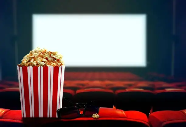 Empty cinema with blank screen, popcorn and 3d glasses