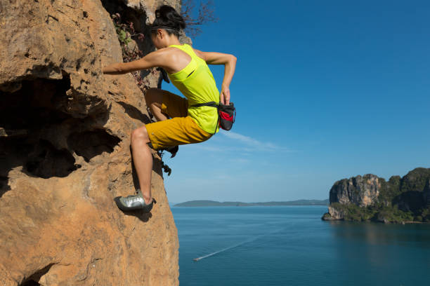 escalador de roca de mujer solo libre escalada en el acantilado junto al mar - escalada en solitario fotografías e imágenes de stock