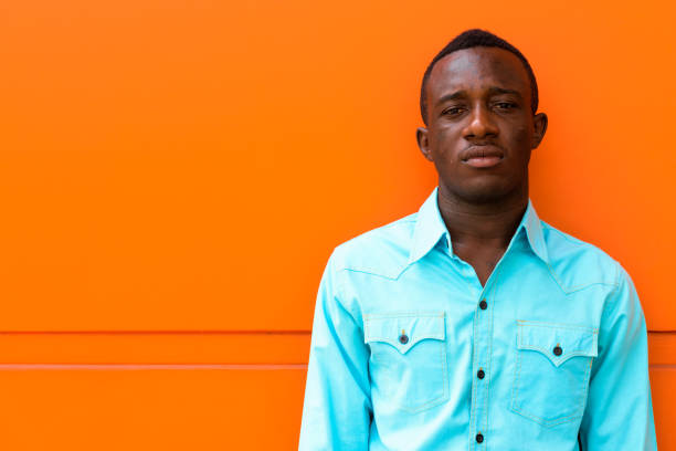 istock Young black African man leaning against orange painted wall 671124434