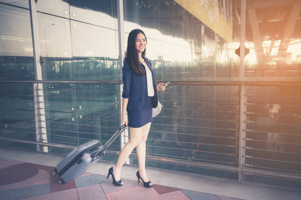 istock Asia businesswoman on commute transit talking on the smartphone while walking with hand luggage in Airport. 671127370