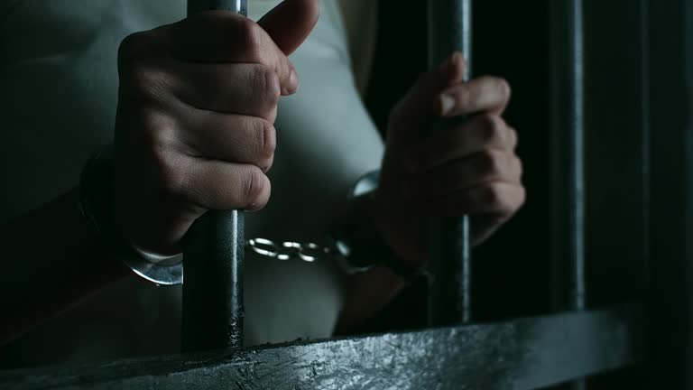 Close-up, women holdin prison bars at prison cell