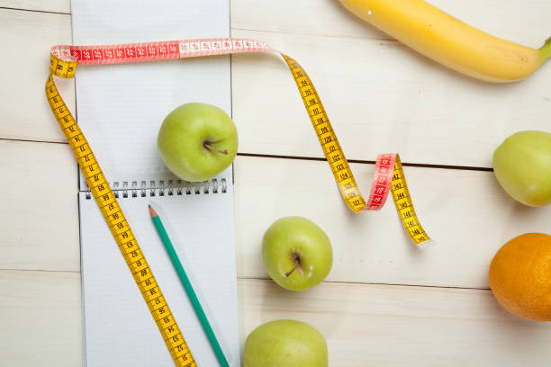 istock Green apples with measuring tape on a white wooden table 671137050